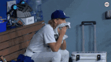 a baseball player is sitting on a bench with a towel on his nose