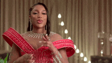 a woman in a red dress with rhinestones and a necklace is making a funny face .