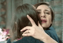 a woman with a ring on her finger is hugging another woman who is crying