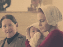 a woman in a head scarf holds a baby