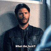 a man with a beard is wearing a leather jacket and tie and says what the fuck .