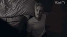 a man in a white t-shirt is laying on a bed with #crypttv written on the bottom