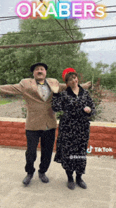 a man and a woman are dancing in front of a sign that says okabers on it