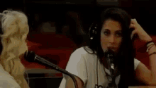 a woman wearing headphones is talking into a microphone while sitting at a table .