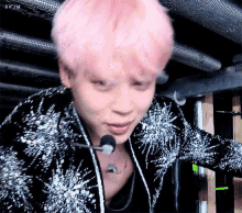 a close up of a person 's face with pink hair and a microphone in their mouth .