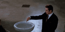a man in a suit and tie is pointing to a bowl of water