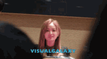 a woman is standing in front of a wall with the words visualgalaxy on it