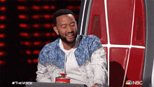 a man is sitting in a chair with a nbc logo on the bottom