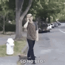 a man is talking on a cell phone while walking down a sidewalk .