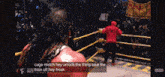 a man in a red hoodie is standing in a boxing ring with a crowd watching