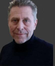 a man with a beard is wearing a black turtleneck sweater and smiling .