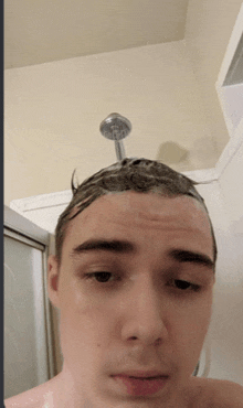 a young man is taking a shower with a shower head on his head