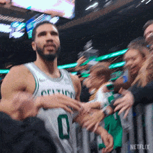a basketball player wearing a celtics jersey stands in front of a crowd