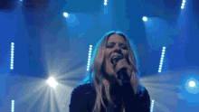 a woman is singing into a microphone on a stage