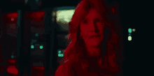 a woman with red hair is standing in a dark room in front of a machine .