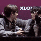 two young men are holding hands in front of a sign that says " xlov "