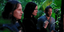 a man and a woman are standing in a jungle .