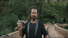 a man holding a sword in front of a forest with pranay varma written on the bottom right