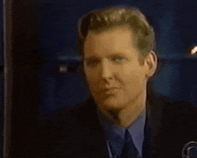 a man in a suit and tie is looking at the camera