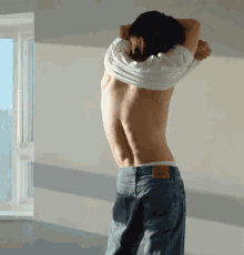 a man wearing a white shirt and blue jeans with a label on the back that says levi 's