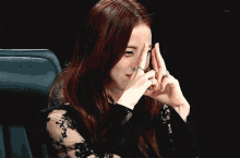 a woman with a ring on her finger is making a peace sign