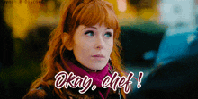 a woman with red hair is wearing a scarf that says okay chef