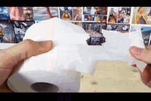 a person is holding a roll of toilet paper in front of a wall with comic strips on it