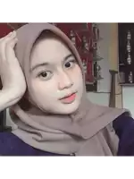 a woman wearing a hijab looks at the camera in front of a wall of bottles