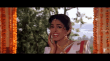 a woman wearing a white and red sari is smiling