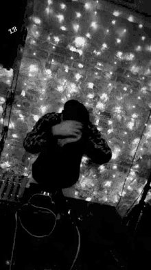 a person covering their face in front of a wall of lights with the letters lb visible