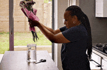 a woman in a blue shirt is holding a bouquet of flowers