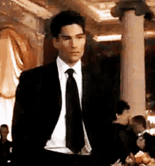 a man in a suit and tie is standing in front of a pillar