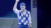 a man wearing a blue and white checkered vest is giving a high five