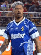 a man wearing a blue rojabet jersey stands on a field