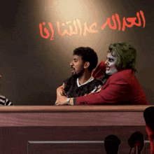 a man in a joker costume sits in a courtroom