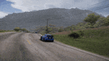 a blue car is driving down a curvy road with mountains in the background
