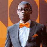 a man wearing an orange bow tie and a grey suit