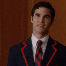 a man wearing a suit and tie with a red stripe on the collar
