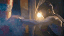a man is boxing in a dark room with a light shining on him .