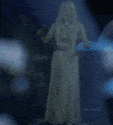 a woman in a long white dress is dancing on a stage