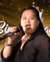 a woman is singing into a microphone and making a face .