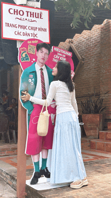 a woman standing next to a cardboard cutout of a man and woman