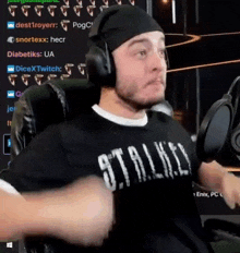a man wearing headphones and a black shirt is sitting in front of a microphone in a chair .