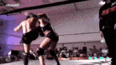 a man and a woman are wrestling in a ring with a referee watching .