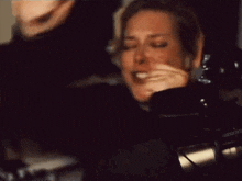 a woman is crying in front of a microphone while sitting in a dark room .