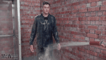 a man is standing in a room with a brick wall and the word mrwam on the bottom