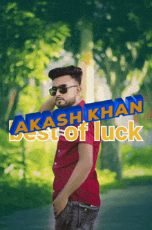 a man wearing sunglasses and a red shirt stands in front of trees with the words " lakash khan best of luck "