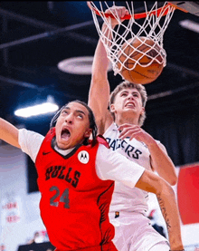 a basketball player wearing a red bulls jersey is dunking a basketball