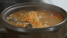 a pot of soup is being cooked on a stove and steam is coming out of it .