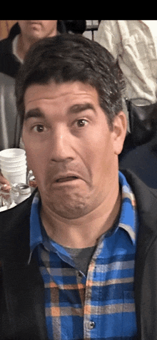 a man in a plaid shirt is making a face